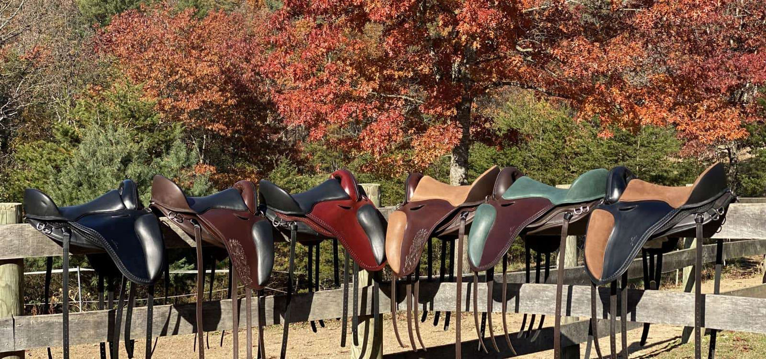 Lineup of six Freeform treeless saddles on a fence - offering balance, freedom & comfort for your horse.